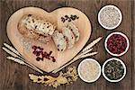 Cranberry seed bread on heart shaped board with wheat and sheaths, sunflower and pumpkin seeds, oatmeal  and dried cranberries over old oak background.
