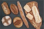 Homemade bread selection on olive wood board on slate background.
