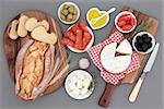 Fresh food selection with chorizio, camembert and feta cheese, olives, tomatoes, oil, herbs and rustic bread on maple boards.