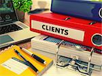 Red Office Folder with Inscription Clients on Office Desktop with Office Supplies and Modern Laptop. Business Concept on Blurred Background. Toned Image.