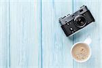 Travel camera and coffee cup on wooden table. Top view with copy space