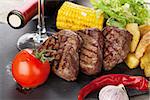 Steak with grilled potato, corn, salad and red wine closeup