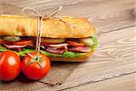 Sandwich with salad, ham, cheese and tomatoes on wooden table