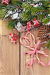 Christmas tree branch with snow and candy canes on wooden table. Top view