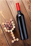 Red wine bottle and glass shaped corks. View from above over rustic wooden table background