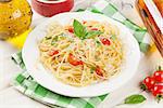 Spaghetti pasta with tomatoes and basil and white wine on wooden table