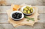 Italian food appetizer of olives, bread and herbs on wooden table background