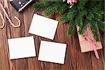 Blank photo frames with christmas gift box, pine tree and camera on wooden table. Top view