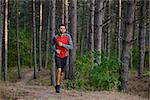 Young Man Running on the Trail in the Wild Pine Forest. Active Lifestyle Concept
