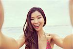 Instagram effect photograph of Asian young woman or girl in bikini, taking vacation selfie photograph at the beach