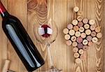 Red wine bottle, glass and grape shaped corks on wooden table background