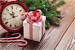 Christmas alarm clock, gift box and fir tree branch on wooden table