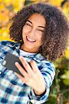 Beautiful happy mixed race African American girl teenager female child smiling with perfect teeth taking selfie photograph with cell phone
