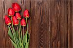 Red tulips bouquet over wooden table background with copy space