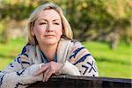 Attractive thoughtful middle aged woman leaning resting on fence in the countryside