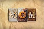 The word "MOM" written in rusty metal letterpress type on a crumbled aged paper background.