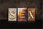 The word "SEX" written in rusty metal letterpress type on a dark textured grunge background.