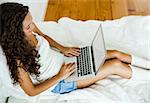 Beautiful woman working with a laptop on the bed