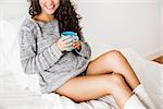 Beautiful woman on bed drinking a coffee