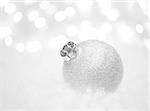 Christmas Decoration with White Ball in the Snow on the Blurred Background with Lights. Greeting Card with Space for Your Text