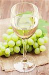 White wine glass and grapes on wooden table