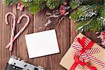 Blank photo frame or greeting card with christmas gift box, pine tree and camera on wooden table. Top view