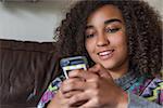 Beautiful happy mixed race African American girl teenager female child smiling with perfect teeth and texting sending text message on cell phone