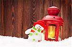 Christmas candle lantern and snowman toy in snow
