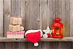 Christmas candle lantern, gift boxes and decor in front of wooden wall with copy space