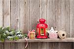 Christmas candle lantern, gifts and decor in front of wooden wall with copy space
