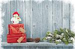 Christmas gift boxes and fir tree branch in front of wooden wall with copy space