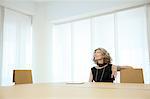 Senior female designer gazing up from boardroom table