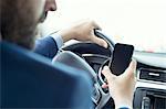 Young businessman reading smartphone text in car