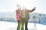 Senior couple on snowy landscape using smartphone to take photograph, Sattelbergalm, Tyrol, Austria