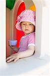 Female toddler looking down from playhouse window