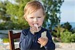 Female toddler eating crisp bread on patio