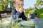 Female toddler eating at table outdoors