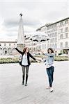 Lesbian couple holding umbrella fooling around holding hands smiling, Piazza Santa Maria Novella, Florence, Tuscany, Italy