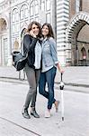 Lesbian couple talking on cellular phone holding umbrella looking at camera smiling, Piazza Santa Maria Novella, Florence, Tuscany, Italy