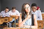 Female student, sitting at desk in classroom, thinking