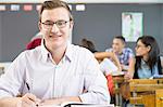 Portrait of male student, sitting at desk in classroom