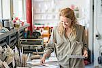 Female print designer examining designs in workshop