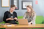 Female printer and designer working with laptop in workshop office