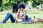 Boy and mother reading and relaxing in park