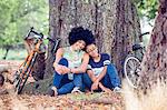 Mature woman and son sitting against park tree