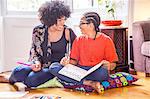 Mature woman and son doing homework on living room floor