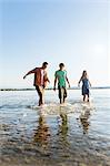 Front view of friends in a row walking ankle deep in water, Schondorf, Ammersee, Bavaria, Germany