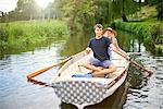 Portrait of young couple rowing on rural river