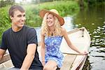 Young couple in rowing boat on rural river