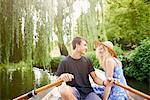 Romantic young couple in rowing boat on rural river